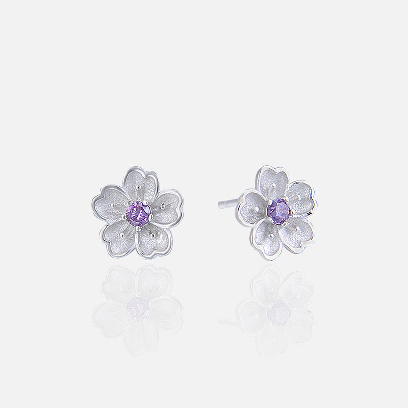 A pair of 925 sterling silver cherry blossom stud earrings with vibrant purple gemstone centers, displayed on a clean white background.