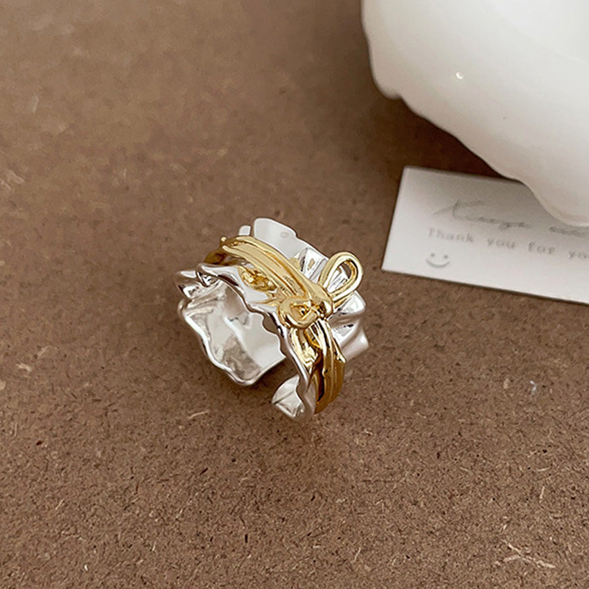 Close-up product photo of the two-tone adjustable bow ring in gold and silver, showcasing its minimalist design and polished brass finish.