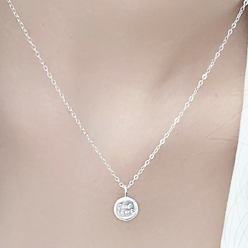 A close-up studio shot of a 925 sterling silver necklace featuring a 'Good Luck' coin charm pendant, on a clean white background.
