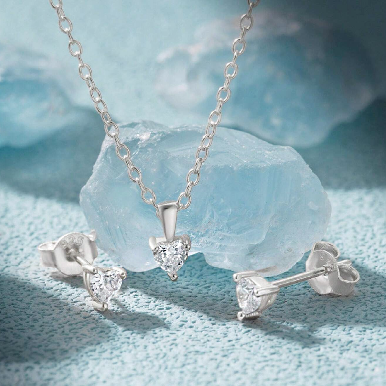 A stunning 925 sterling silver jewelry set featuring a heart-shaped zircon necklace and matching stud earrings, elegantly displayed.