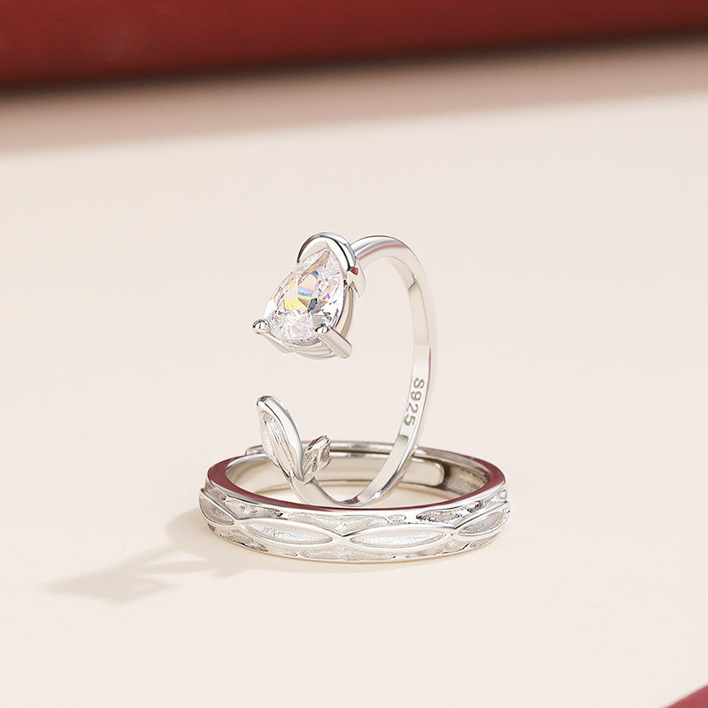 A beautifully detailed 925 sterling silver couple promise ring set, one featuring a heart-shaped stone and the other an intricate band design.