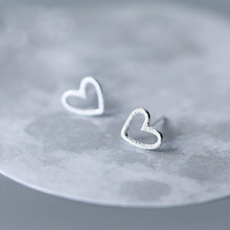 A pair of 925 sterling silver hollow heart stud earrings with a textured finish, displayed on a clean white background.