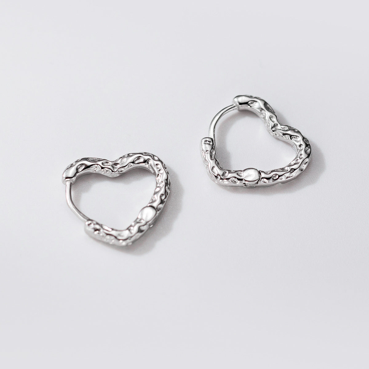 A pair of wholesale 925 sterling silver heart hoop earrings with a minimalist textured design, shown on a clean background.