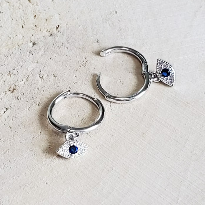 A pair of 925 sterling silver evil eye hoop earrings with sparkling blue zircon charms on a white background.