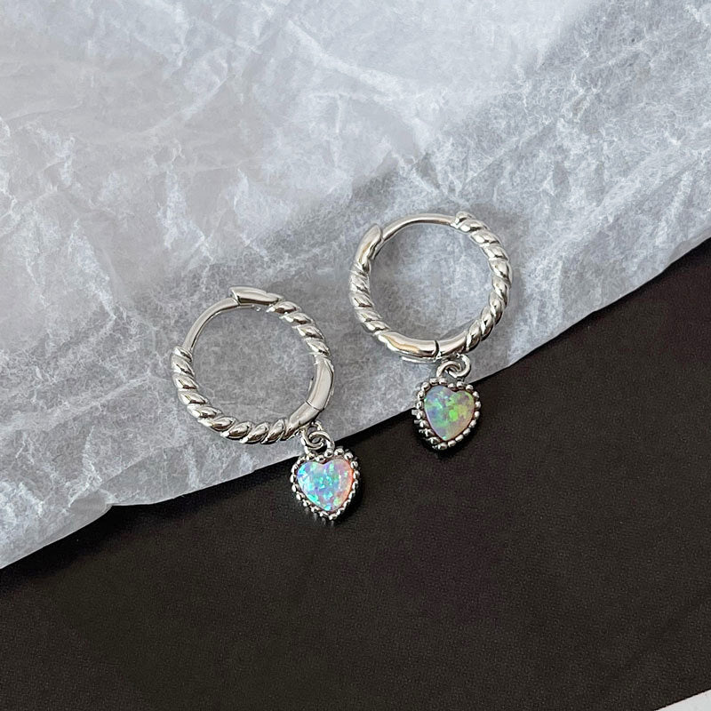 A pair of 925 sterling silver huggie hoop earrings with charming heart-shaped opal stone pendants, displayed on a neutral background.