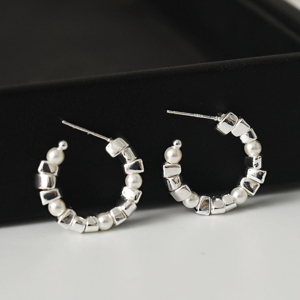 A pair of silver-plated C hoop earrings featuring an elegant combination of white pearls and small square beads, on a clean white background.