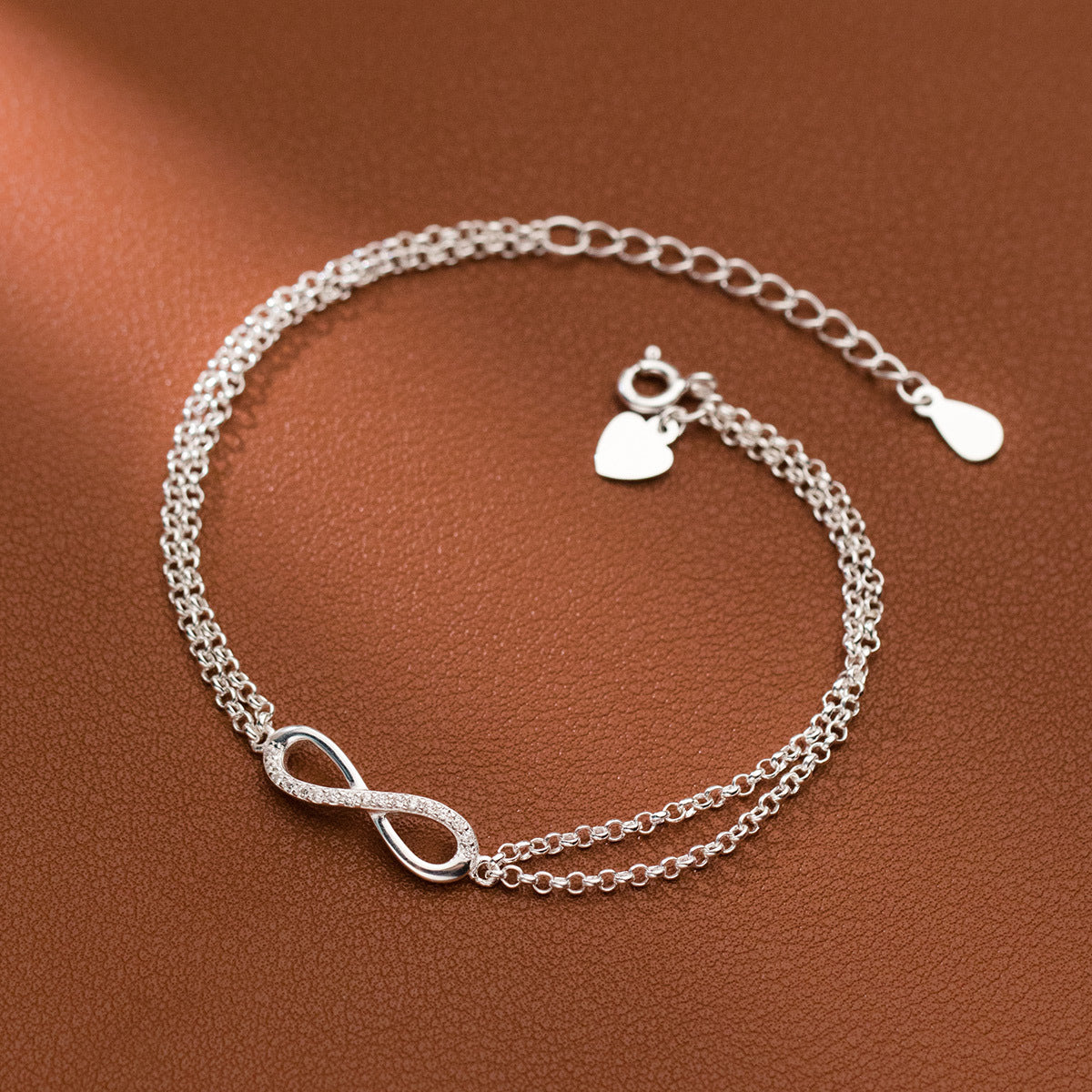 A close-up of the 925 Sterling Silver Infinity Symbol Double Chain Bracelet, featuring a delicate heart charm.
