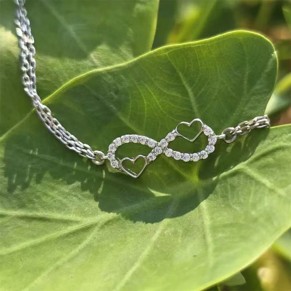 Close-up of a 925 sterling silver infinity heart bracelet with a double chain, adorned with sparkling cubic zirconia gemstones.