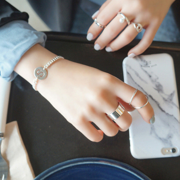 A woman's hands wearing a stack of minimalist 925 sterling silver wide band rings, showcasing a trendy Korean-style look for wholesale jewelry.