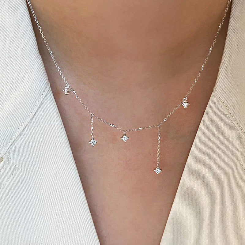 A close-up of a delicate 925 sterling silver clavicle necklace from the wholesale set, featuring five sparkling zircon charms.
