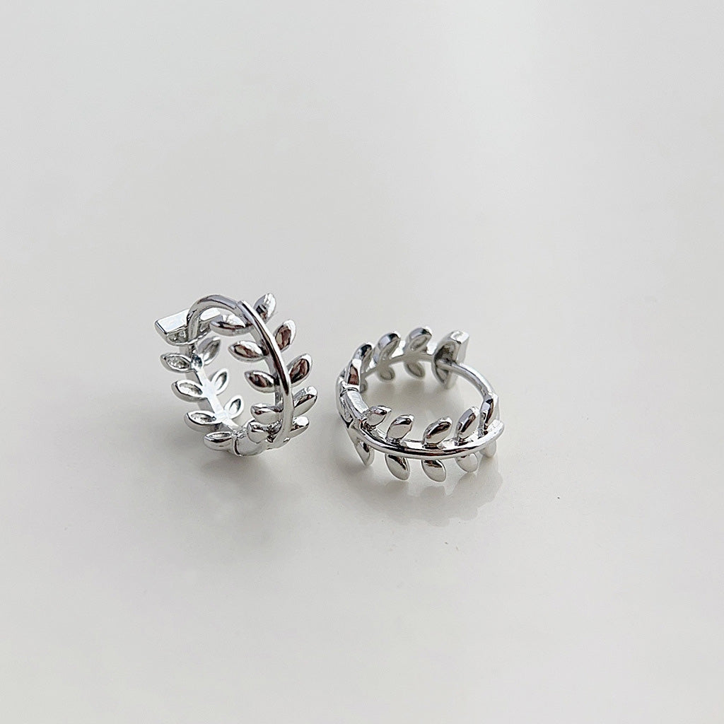 A pair of silver plated tiny hoop earrings designed in a delicate leaf wreath pattern, shown against a clean white background.
