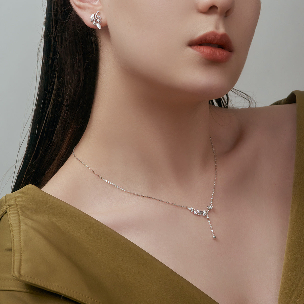 A stunning set of 925 sterling silver jewelry, featuring a leaf tassel pendant necklace with a delicate pearl and matching earrings, displayed on a neutral background.