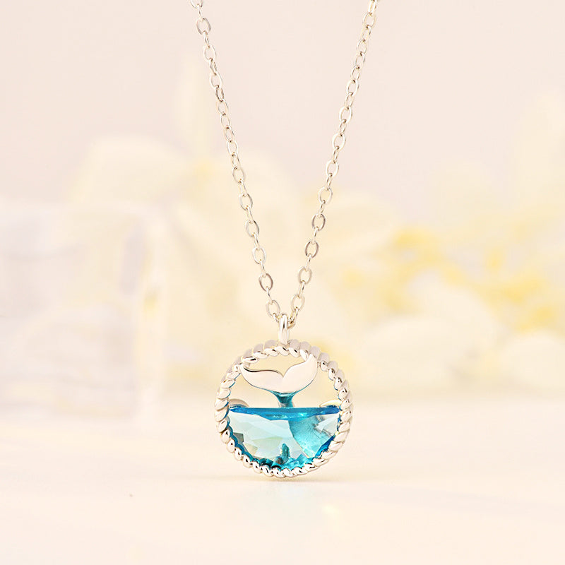 A delicate 925 sterling silver necklace featuring an elegant mermaid tears whale tail pendant with a blue gemstone, displayed on a neutral background.