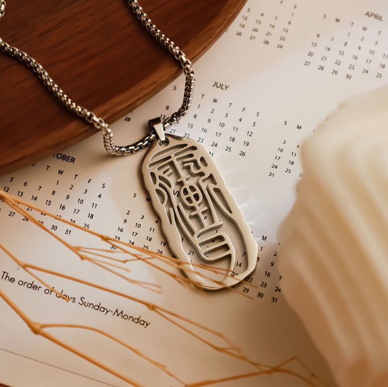 A custom silver necklace from JR Fashion Accessories, featuring an elegant oval pendant engraved with traditional Chinese symbols.