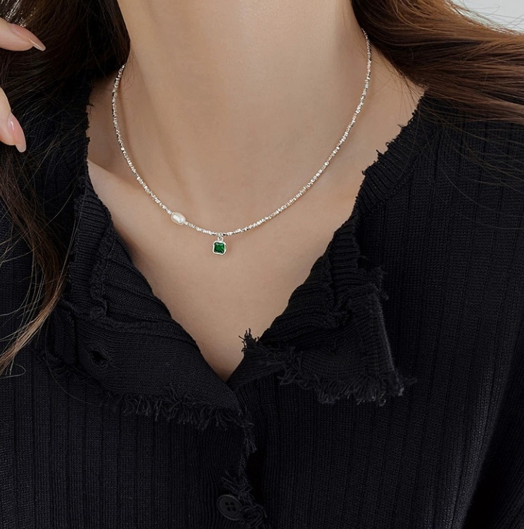 A model wearing the 925 Sterling Silver Pearl Emerald Necklace, showcasing the brilliant green pendant against a black top.