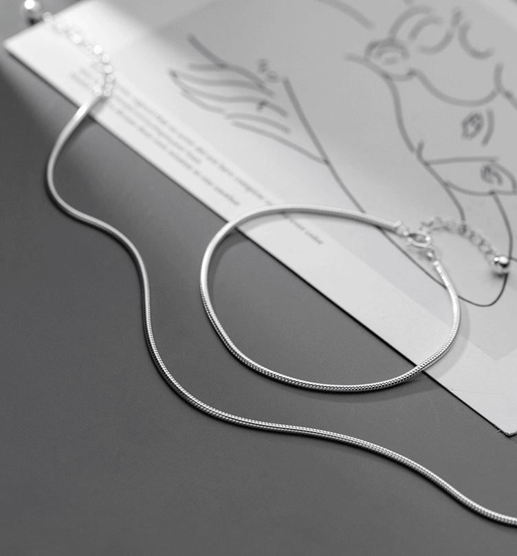 A pair of 925 sterling silver round snake chain necklaces displayed elegantly on a decorative tray.