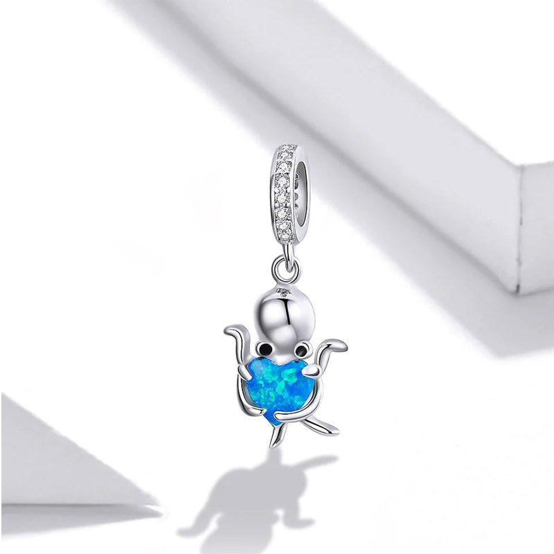Close-up of a 925 sterling silver octopus charm holding a vibrant blue heart-shaped opal, part of the ocean-themed pendant set.