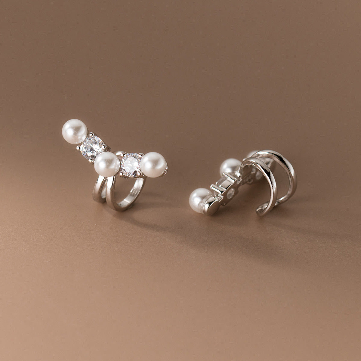 A pair of 925 sterling silver pearl ear cuffs with delicate gemstone accents, showcased on a white background.