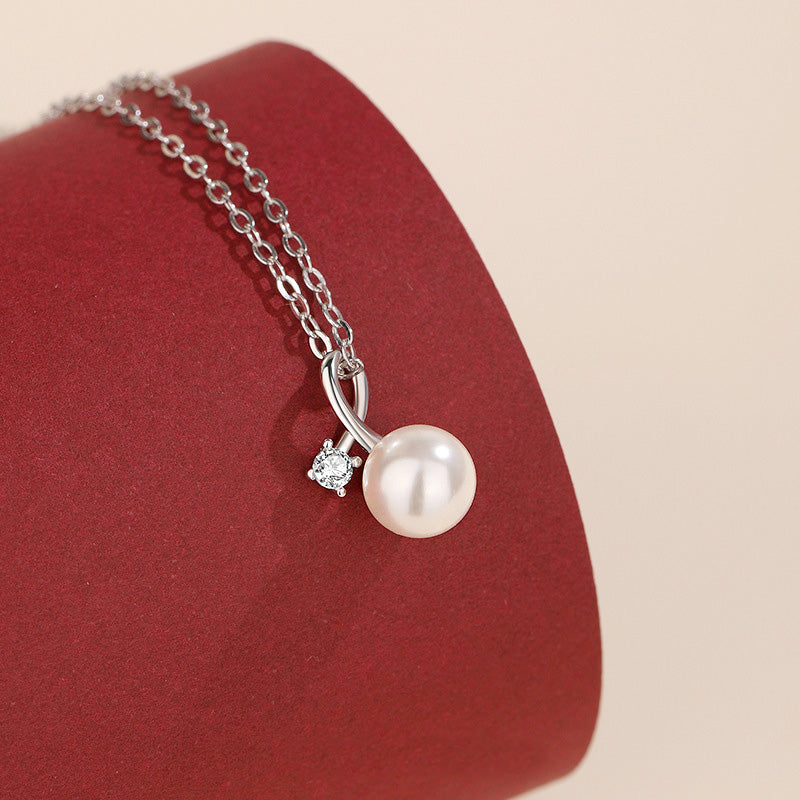 A close-up of a 925 sterling silver necklace featuring a classic white pearl pendant accented with a brilliant, sparkling cubic zirconia charm.