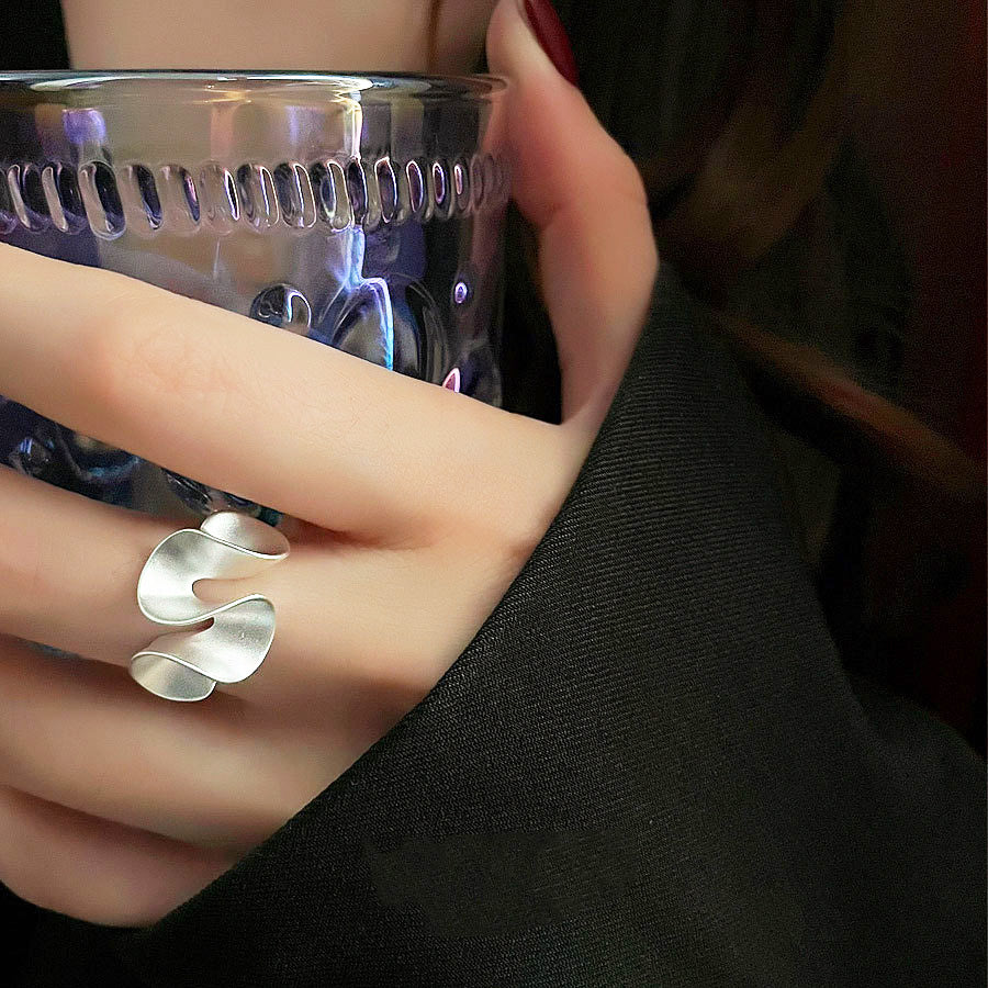 A close-up product shot of an S925 sterling silver ring from a set of five, featuring an irregular, wrinkled texture inspired by a lotus leaf.