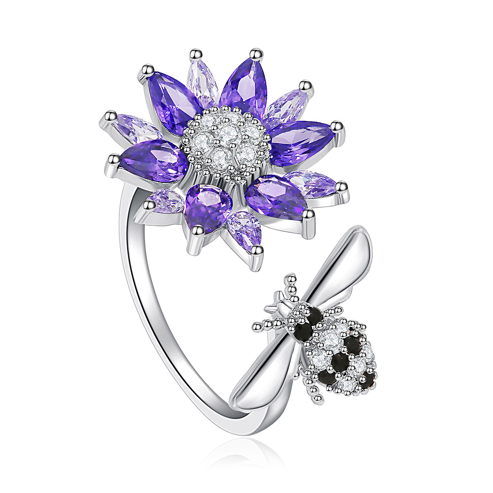 Close-up of the Spinning Purple Flower Ring, showing the rhodium-plated brass band, purple and clear cubic zirconia flower, and detailed bee charm.
