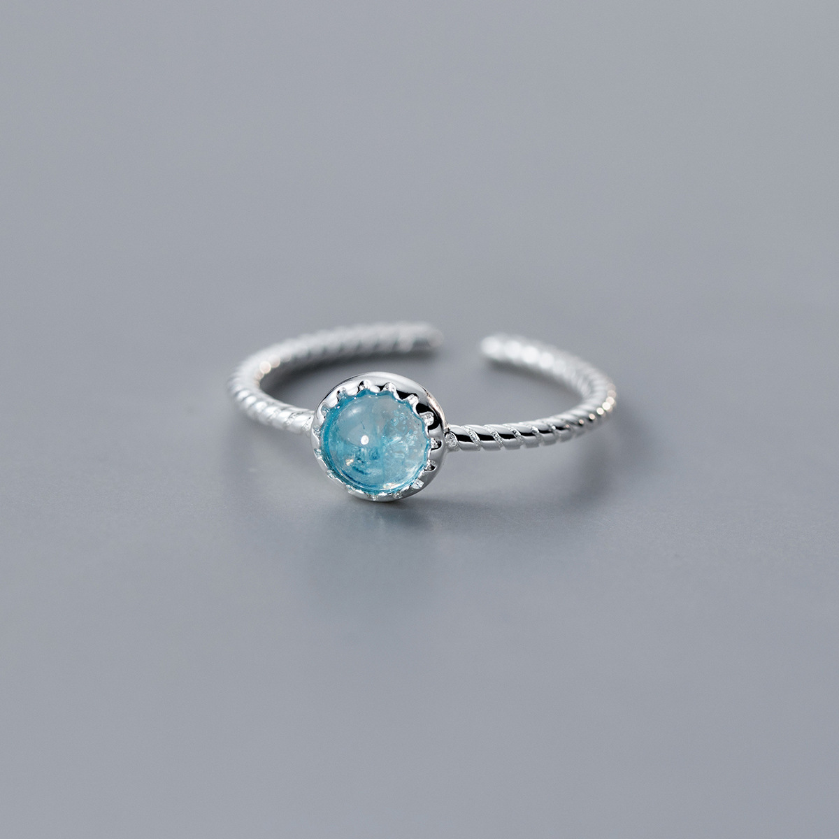 A close-up of an elegant 925 sterling silver adjustable ring featuring a light blue aquamarine gemstone, part of a wholesale stackable set.