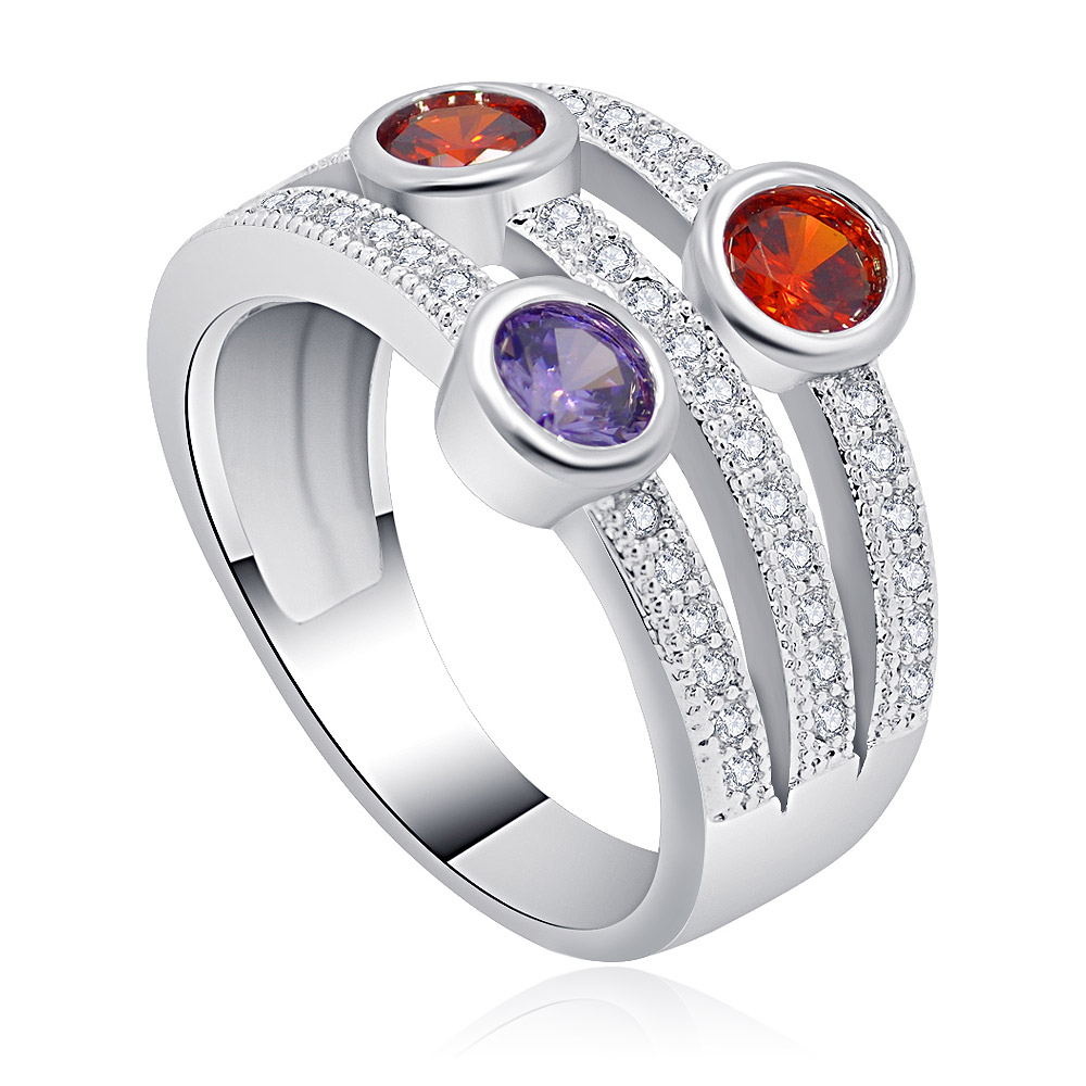 A close-up of the Multi-Gemstone Bubble Ring, featuring two vibrant orange and one deep purple cubic zirconia stones set in a polished, rhodium-plated brass band with sparkling diamond embellishments.