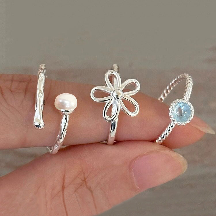 A collection of four unique 925 sterling silver open rings from the Fresh Sweet Bloom series, featuring twisted band, pearl, flower, and blue gemstone designs.