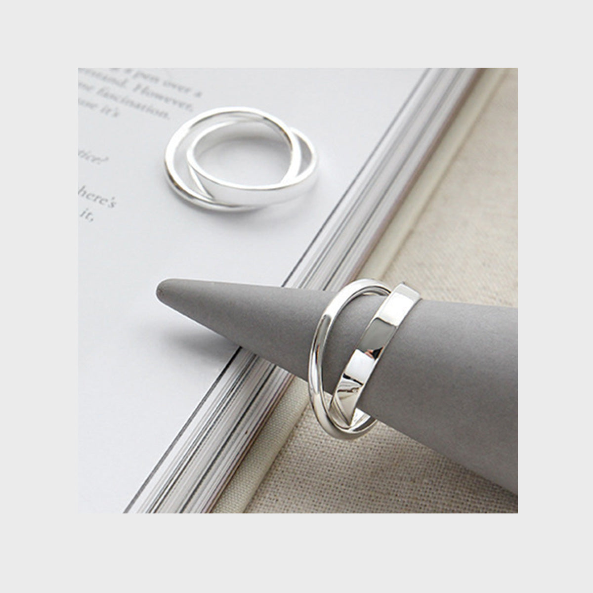 A set of 925 sterling silver double loop rings with a minimalist Korean design, displayed on a white cone for wholesale jewelry.