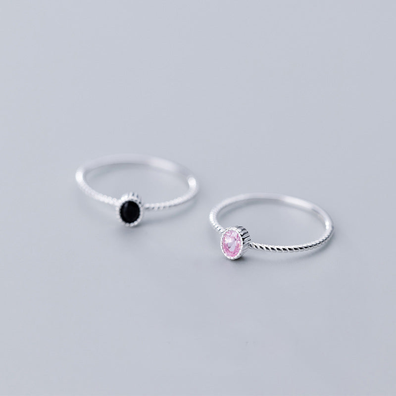 A set of two 925 sterling silver rings, one with a single black cubic zirconia stone and the other with a pink one, displayed on a white background.