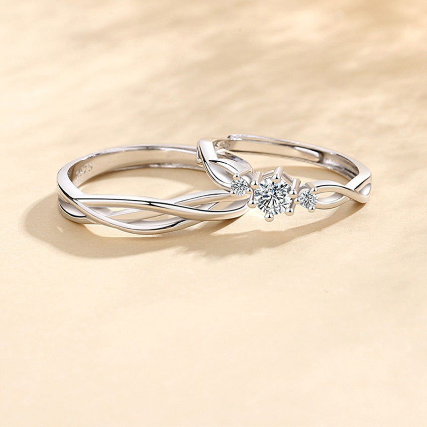 A stunning pair of 999 sterling silver couple rings with a twisted design, the women's ring featuring a brilliant central cubic zirconia stone.
