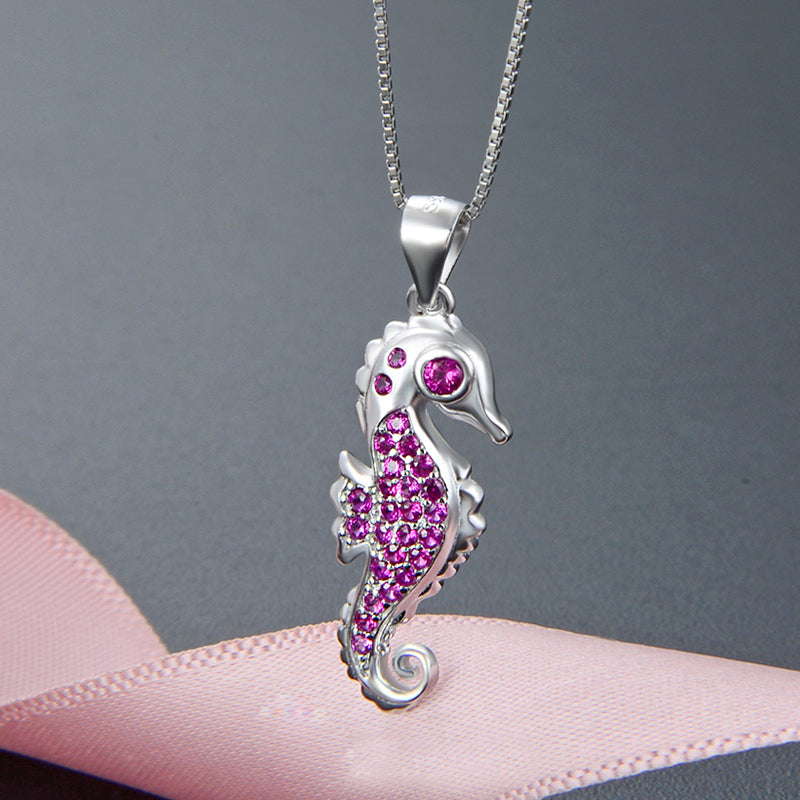 A detailed close-up of a 925 sterling silver seahorse pendant, intricately designed and embellished with vibrant pink cubic zirconia stones.
