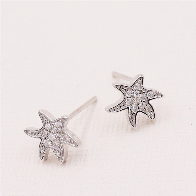 A pair of 925 sterling silver starfish earrings, intricately detailed with small clear gemstones, presented on a clean white background.