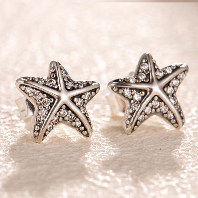 A close-up view of a pair of 925 sterling silver vintage starfish stud earrings, showcasing the intricate details and sparkling clear gemstones.