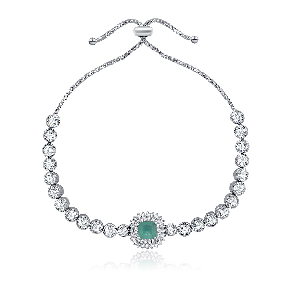A close-up of the Glitter Adjustable Tennis Bracelet, showcasing the central green cubic zirconia stone surrounded by clear stones in a silver-toned rhodium plated setting.