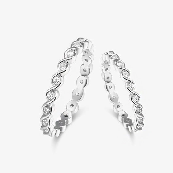 A close-up of a set of five 925 sterling silver stackable rings with a petite twist band design, each sparkling with cubic zirconia stones.