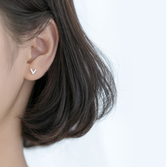A woman wearing the elegant 925 Sterling Silver V Letter Earrings, showcasing their stylish fit and design.
