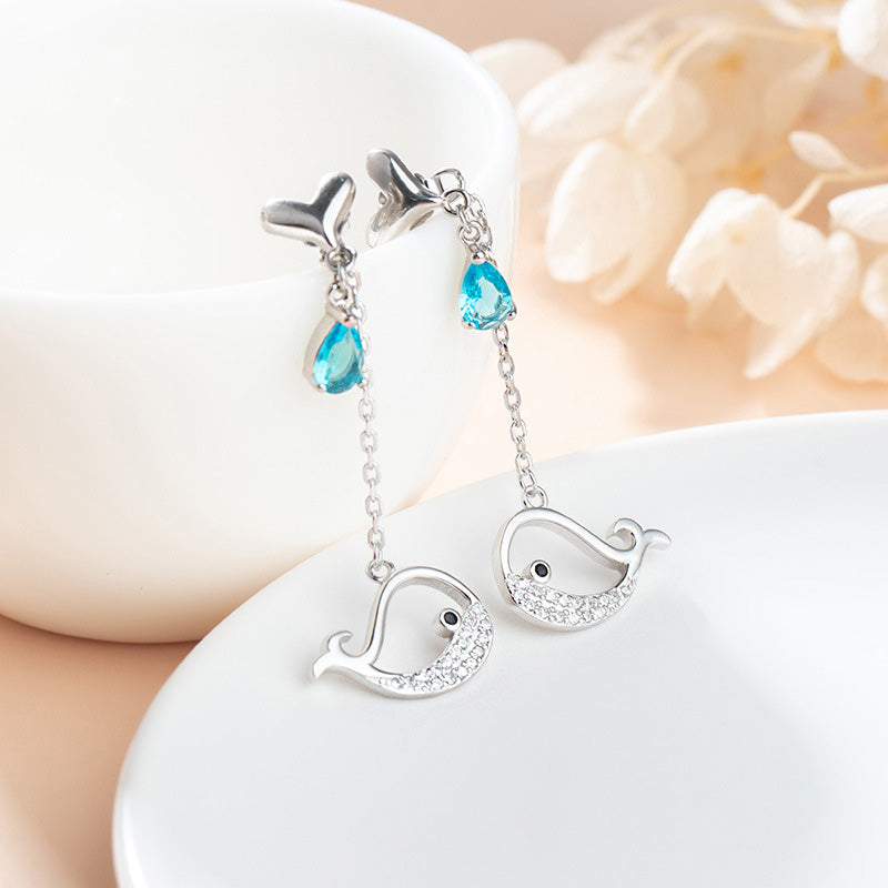 Close-up of 925 sterling silver whale chain drop earrings, highlighting the detailed whale charms and sparkling sea-blue gemstones.