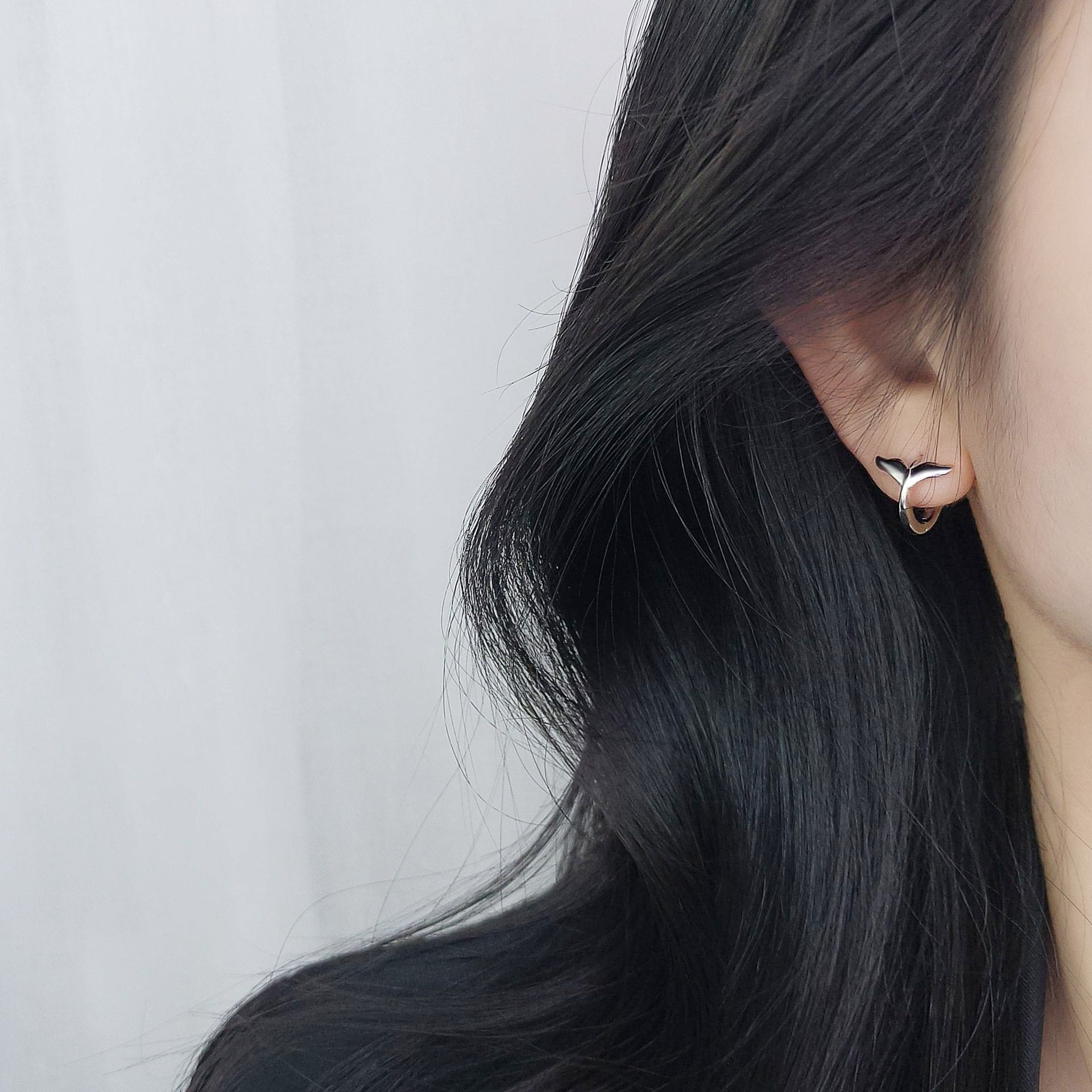 Close-up of a 925 sterling silver ocean mermaid fishtail huggie hoop earring being worn, showcasing its elegant design.