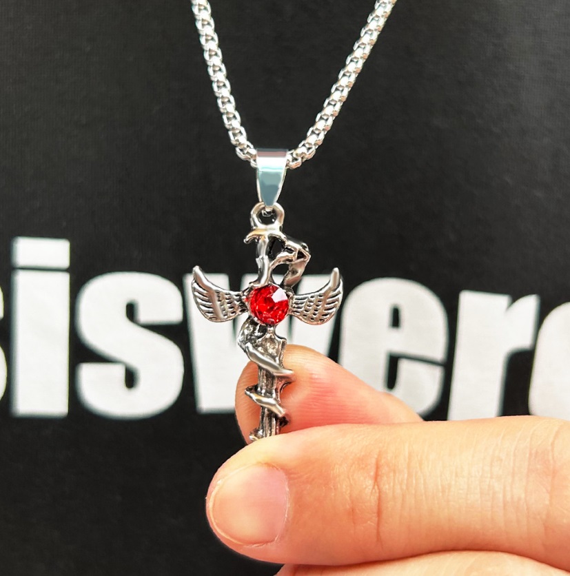 A striking stainless steel Angel Wing Necklace for men, showcasing a detailed winged cross pendant centered with a vibrant red gemstone.