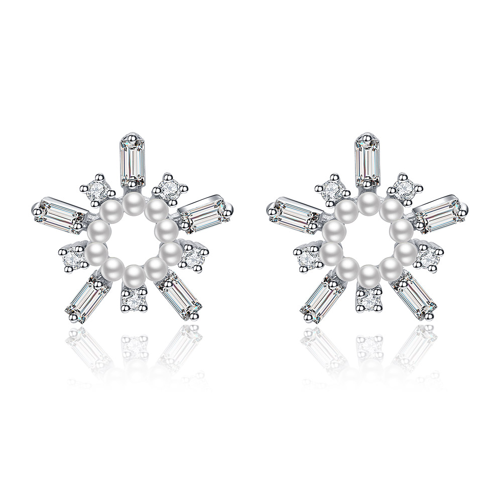 A close-up of the White As Snow Pearl Earrings, showcasing the intricate snowflake design with a central white pearl and sparkling cubic zirconia stones on a white background.