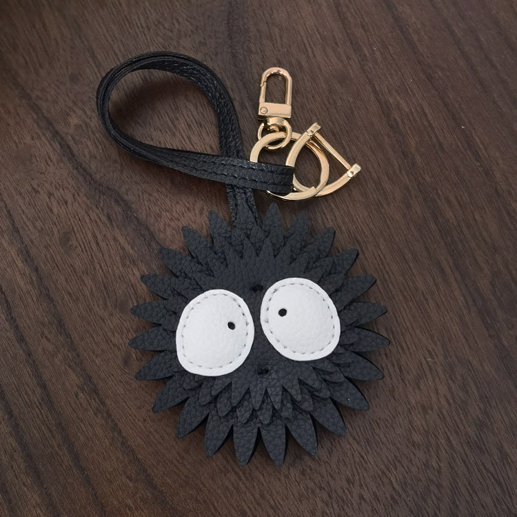 A close-up of the Soot Sprite PU leather bag charm, showing its black, spiky texture and large white eyes, inspired by classic animation.