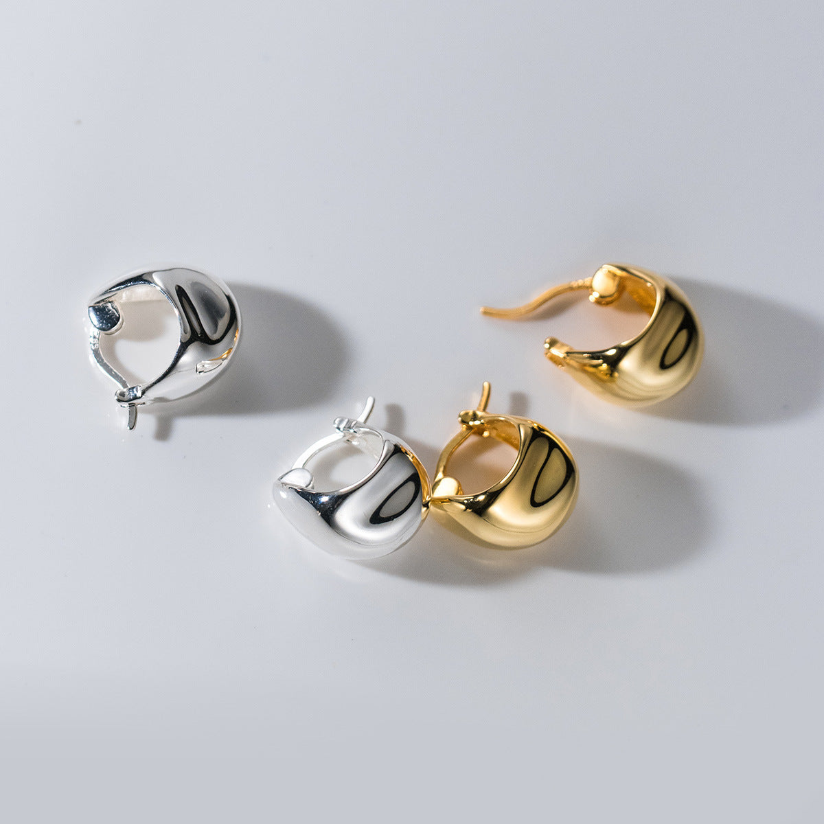 A promotional product shot of S925 sterling silver irregular geometric huggie hoop earrings, displaying three pairs in both silver and gold finishes.
