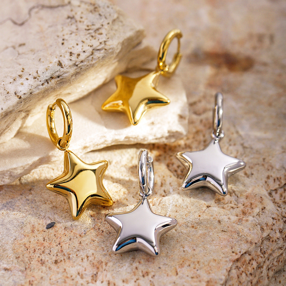 A set of stainless steel star dangle huggie drop earrings, showcasing both the elegant gold and sleek silver finishes against a clean white background.