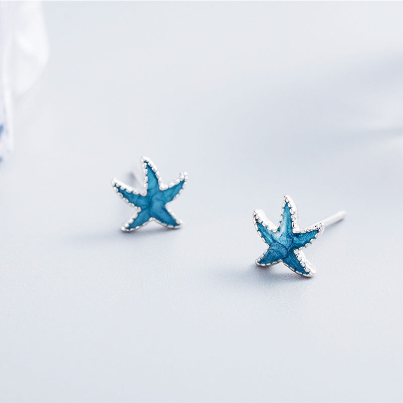 A pair of 925 sterling silver starfish stud earrings with vibrant blue enamel detailing, shown on a clean white background.