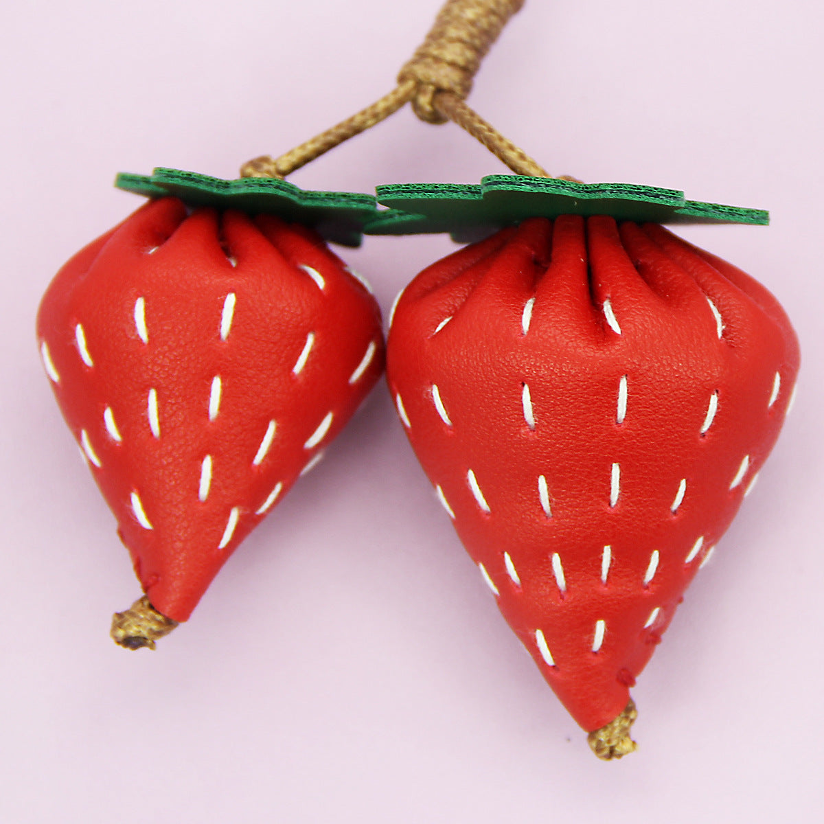 A pair of detailed, hand-stitched PU leather strawberry keychains, showcasing their 3D shape and vibrant red color against a white background.