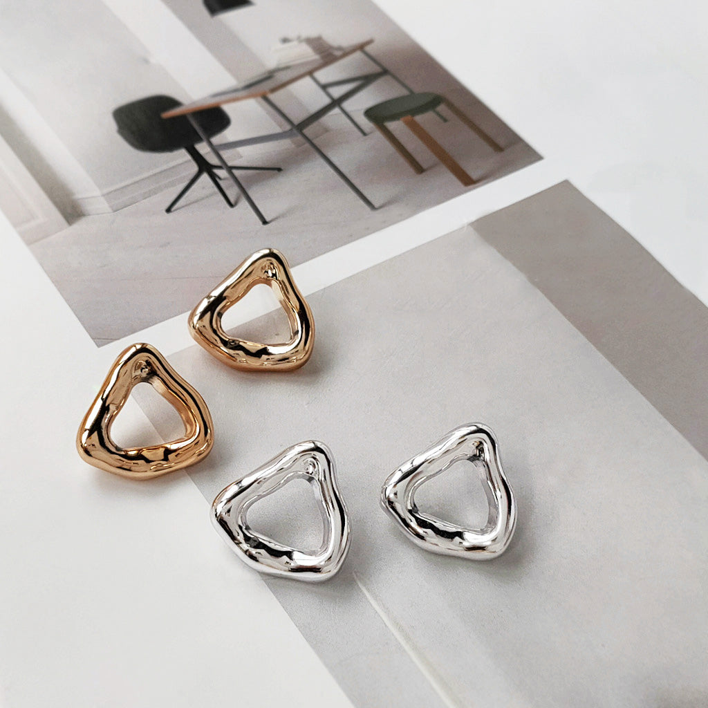 A pair of gold and a pair of silver geometric curve triangle hoop earrings displayed side-by-side on a white background.