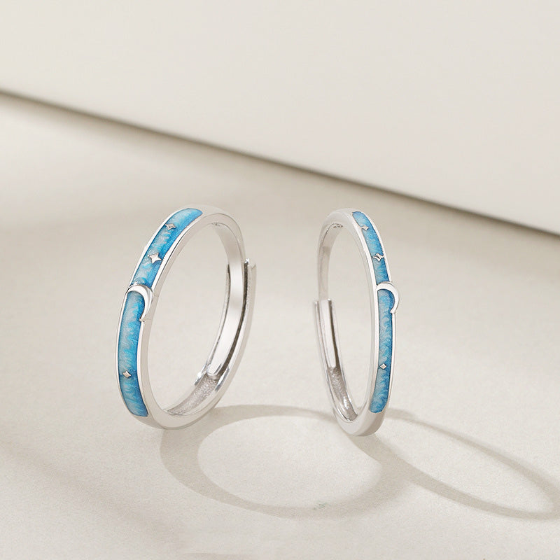 A pair of 925 sterling silver adjustable couple rings with a celestial star and moon design highlighted by blue enamel.