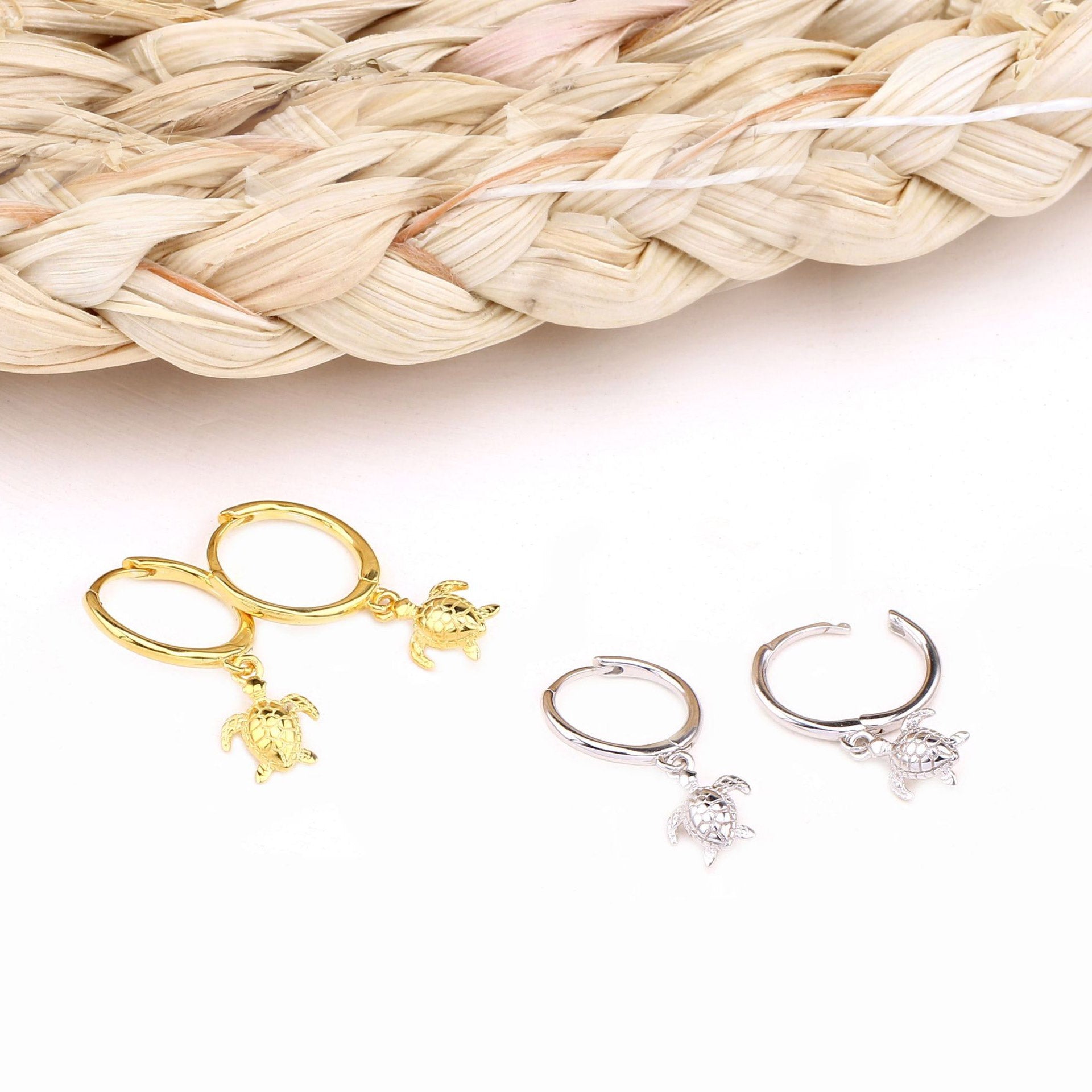 A pair of 925 sterling silver ocean turtle huggie hoop earrings shown in both gold and silver finishes, highlighting the detailed turtle charm design.
