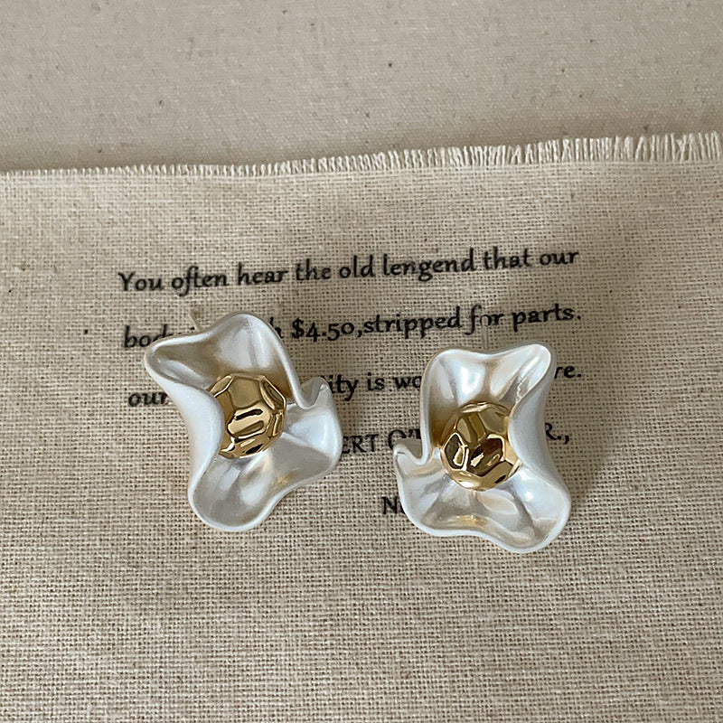 A pair of Gold Petal Brass Earrings with a matte white finish and a polished gold metal center, displayed on a neutral background.